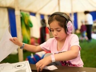 Kind met grote gehoorbeschermer werkt aan een tafel in een tent
