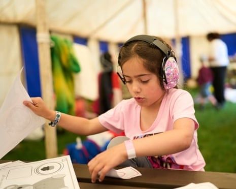 Kind met grote gehoorbeschermer werkt aan een tafel in een tent