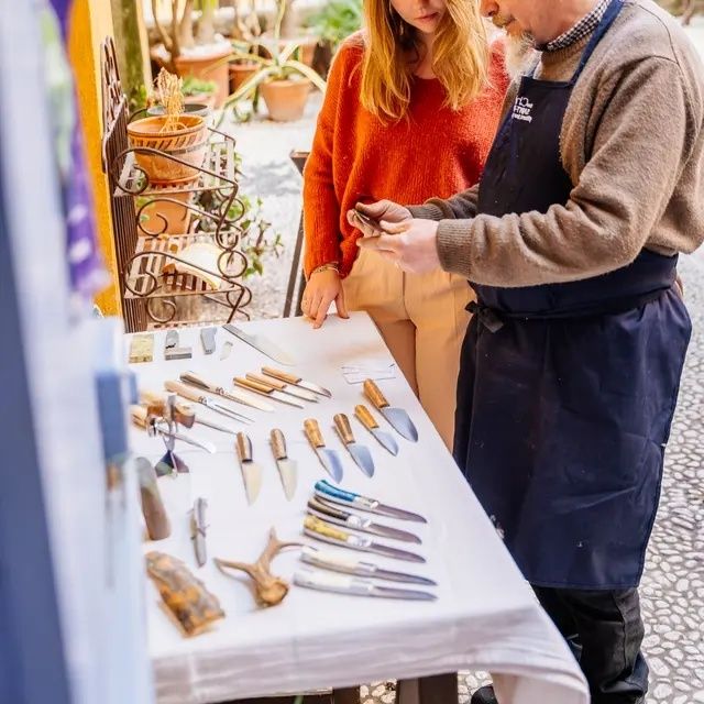 Bezoekers bekijken handgemaakte messen en gereedschap op een fantasyfair