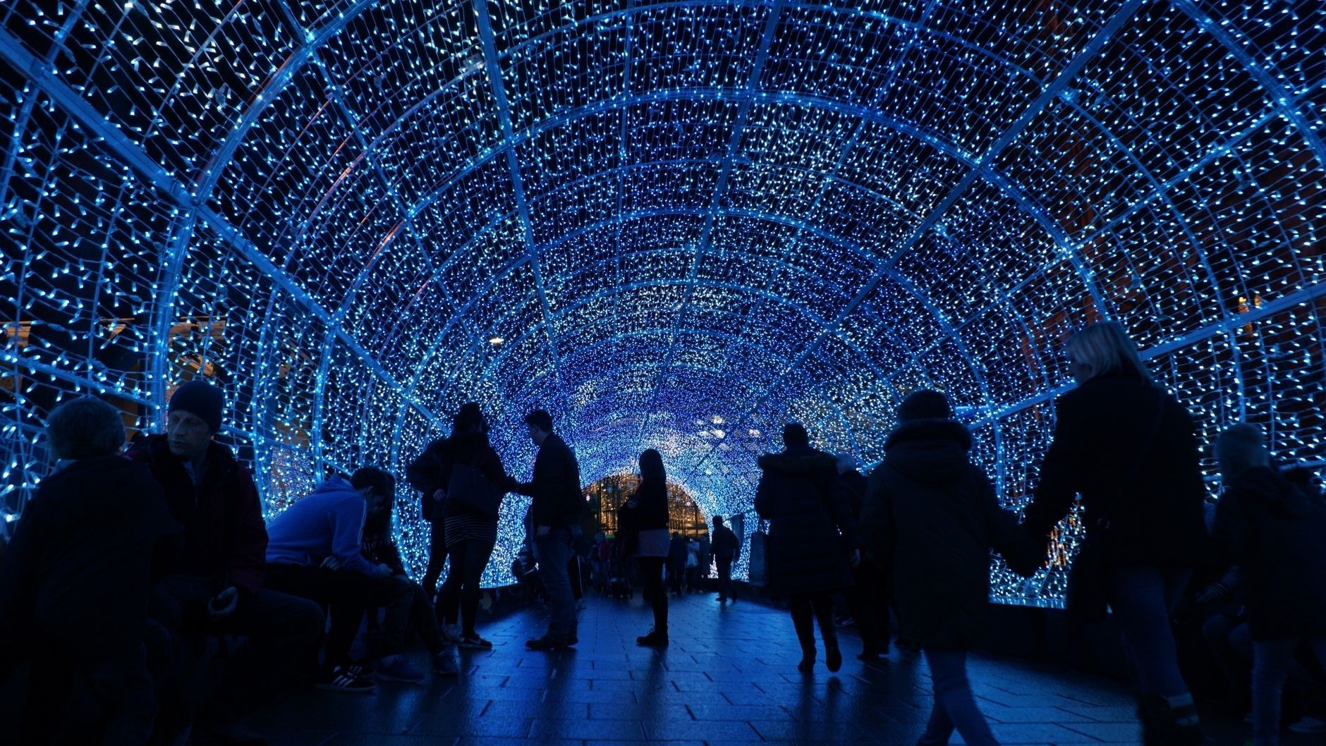 Bezoekers wandelen door een tunnel vol blauwe lichtjes