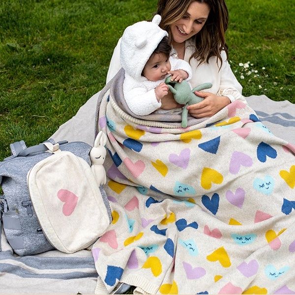 Moeder houdt haar baby warm onder een zachte deken op het gras